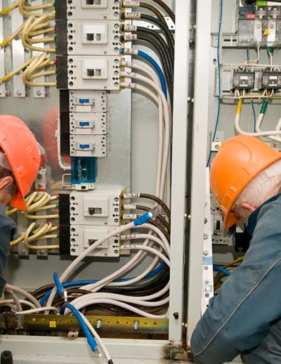 Two electricians working on a industrial panel mounting and assembling new wiring