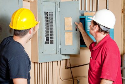 two electricians checking electrical panel