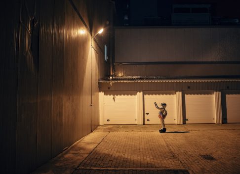 Spaceman standing under lamp at a yard at night