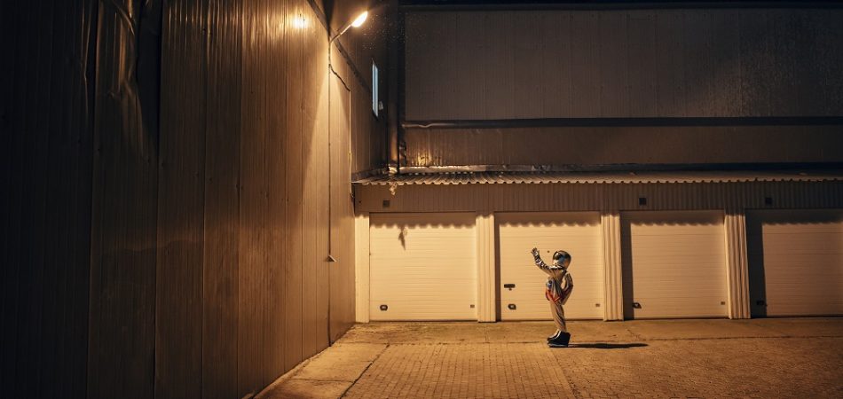 Spaceman standing under lamp at a yard at night